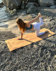 Posizione pilates all'aperto con tappetino Fitnexfly in sughero e gomma, donna in equilibrio su una gamba piegata e una mano